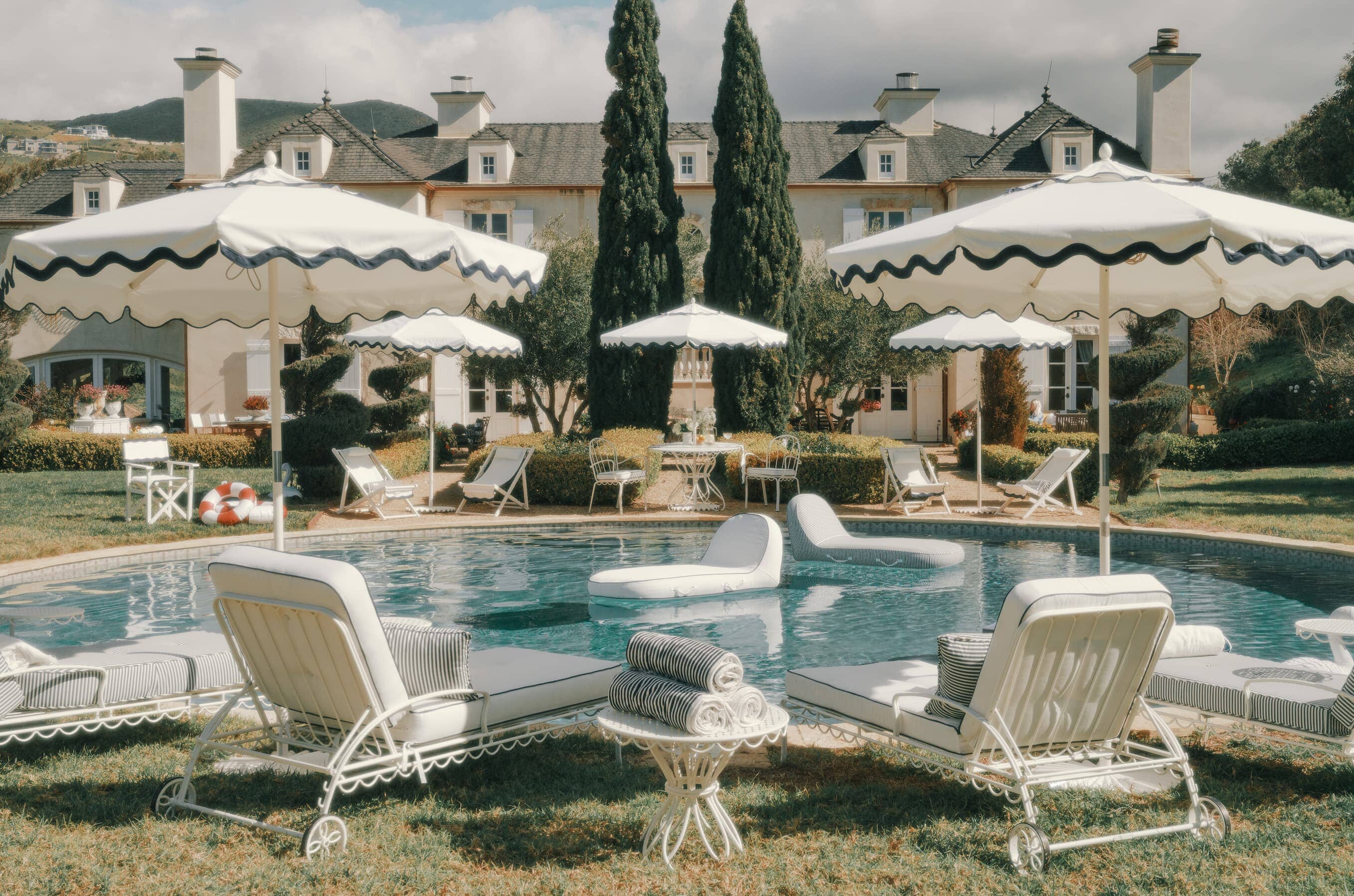 Directors chairs, umbrellas, sun loungers and tables around a pool