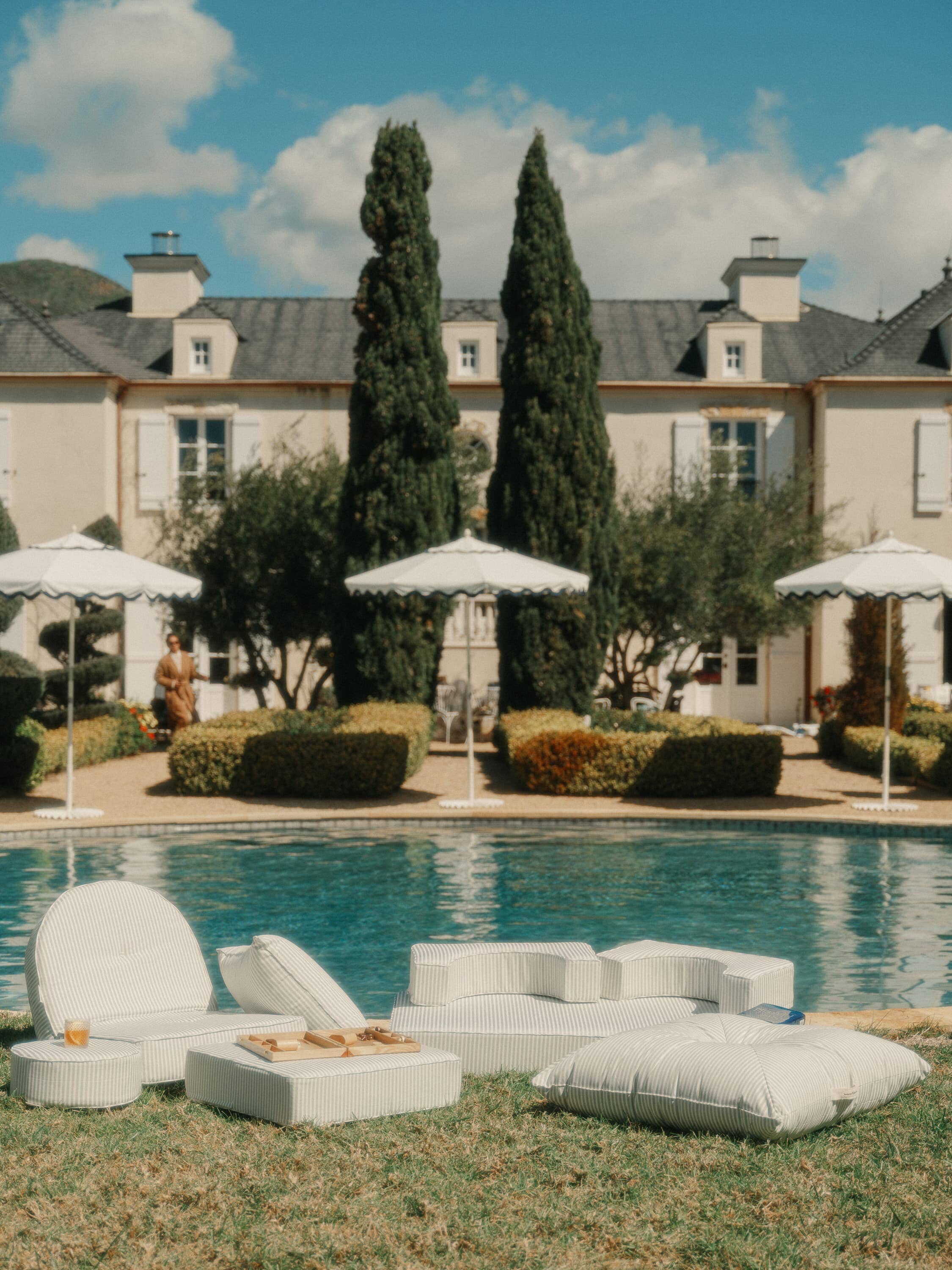 Outdoor pool setting with pool, umbrellas and outdoor cushions
