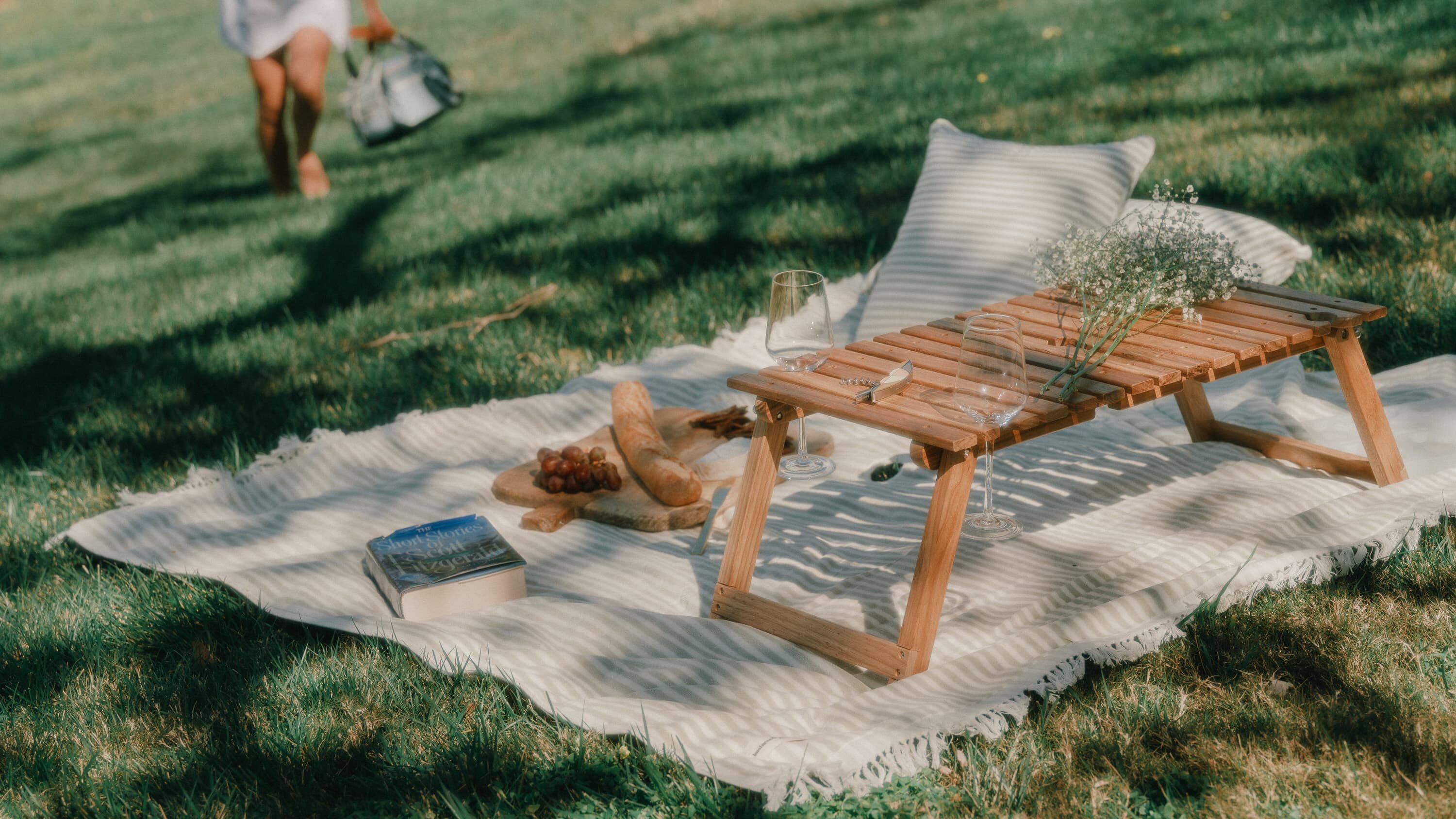 Picnic set up with folding table, cooler, blanket and cushions.