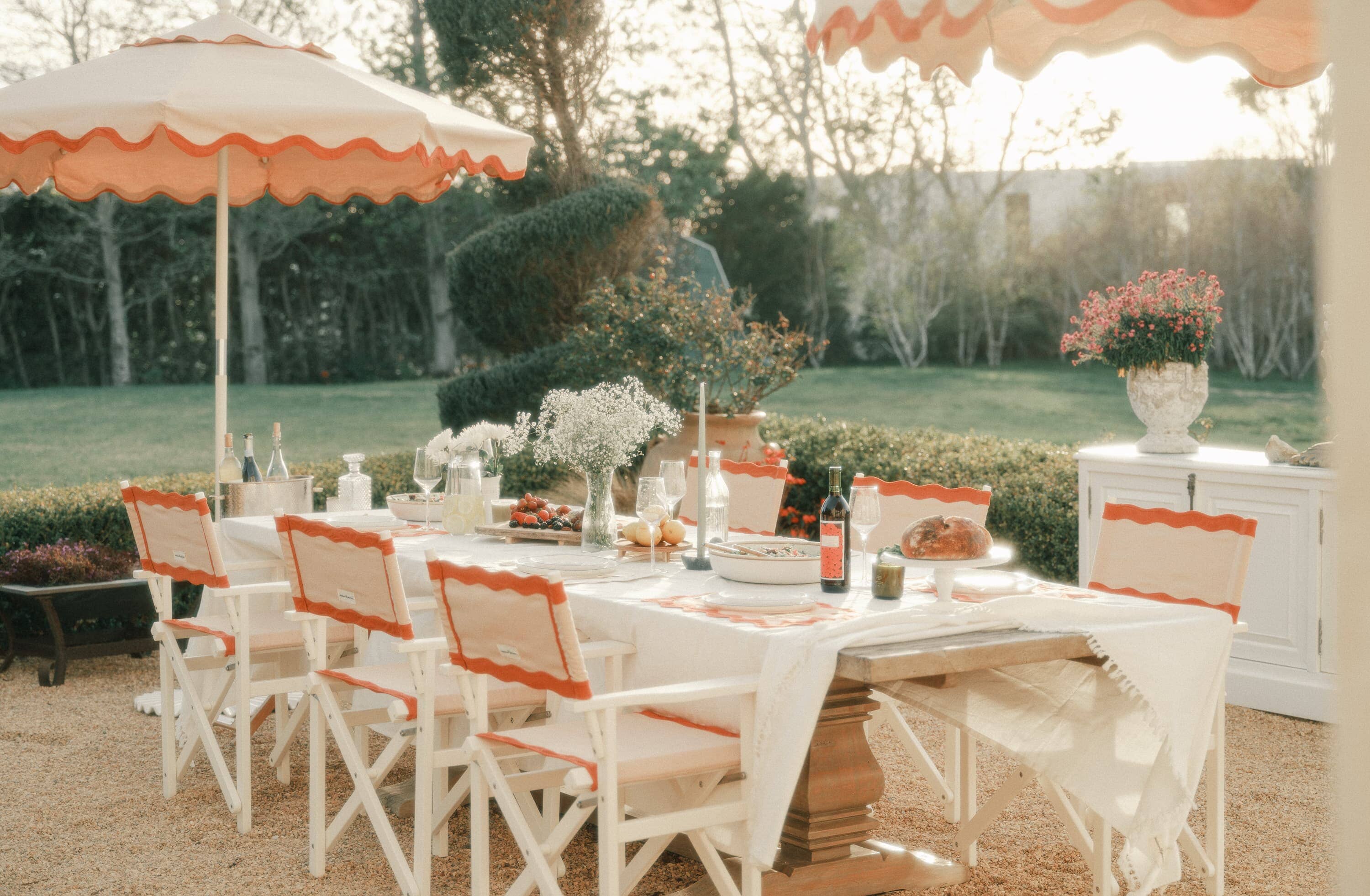 Al fresco dining table with white table cloths and riviera pink chairs and umbrella