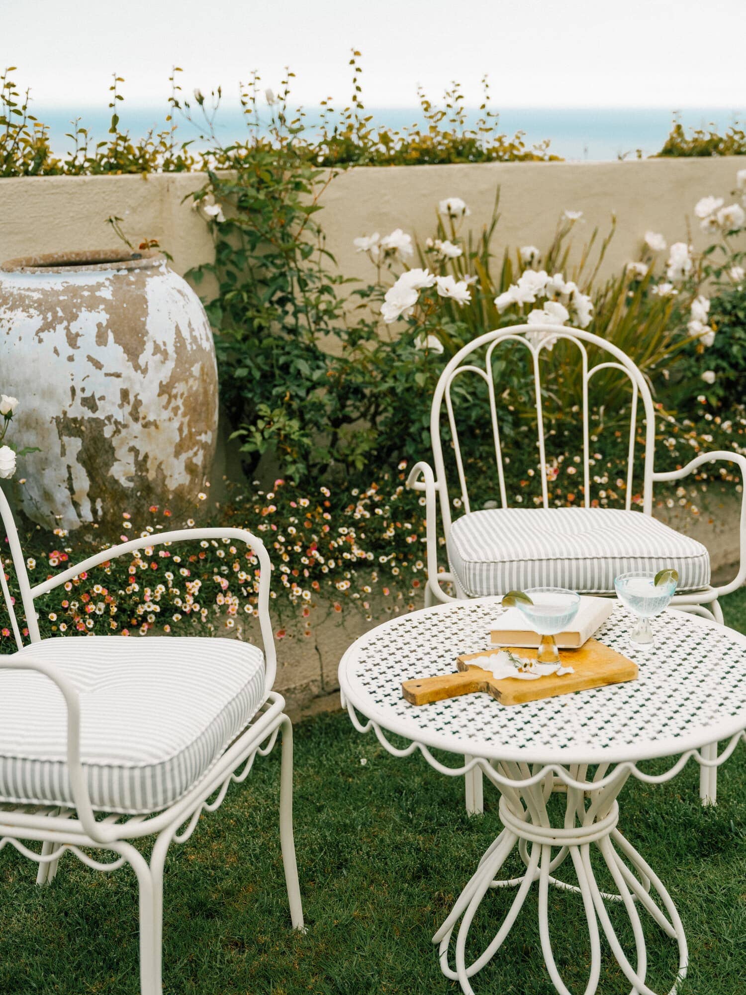 White al fresco chairs and side table in a garden