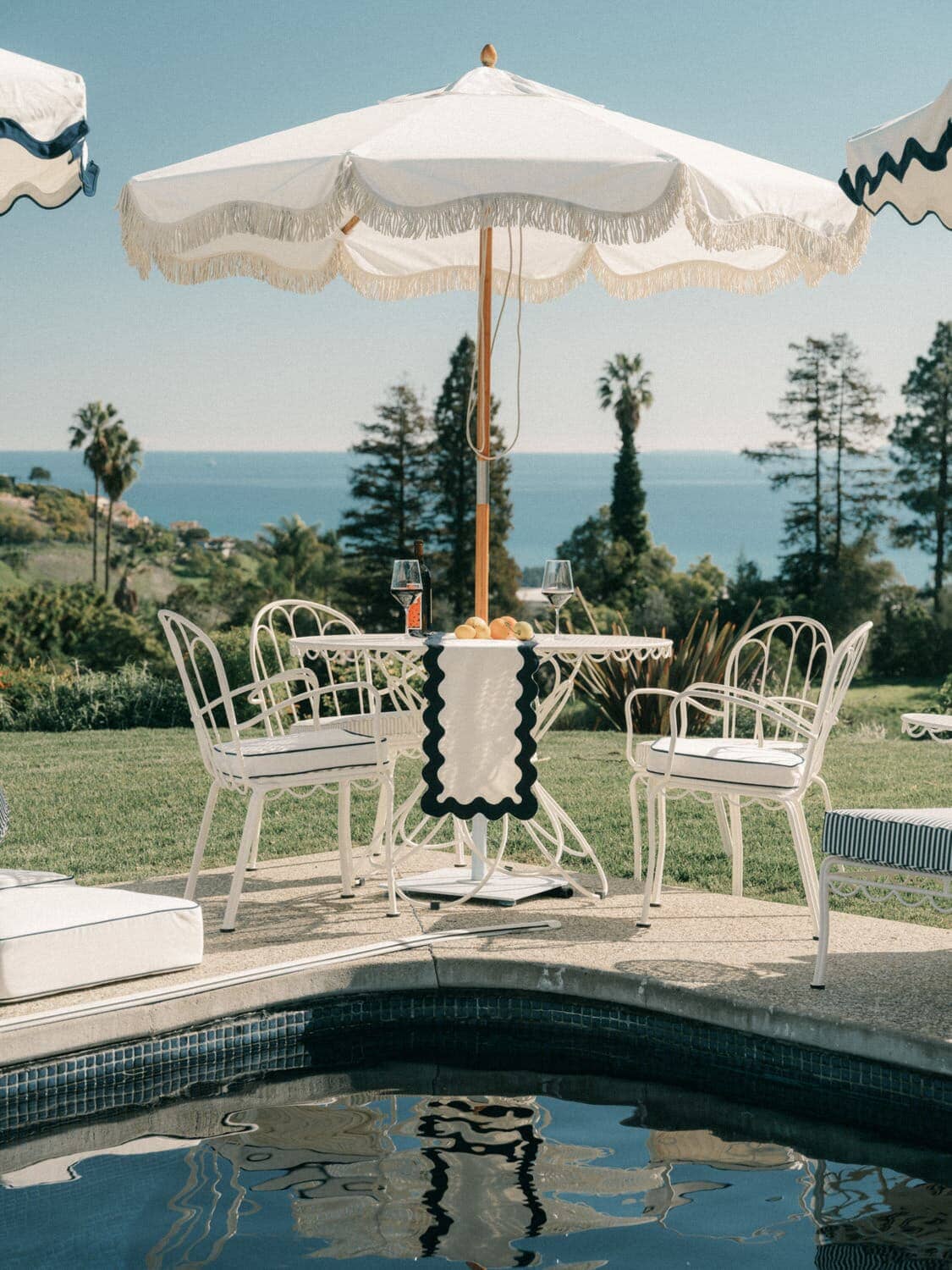 White table, chairs and umbrella next to a pool