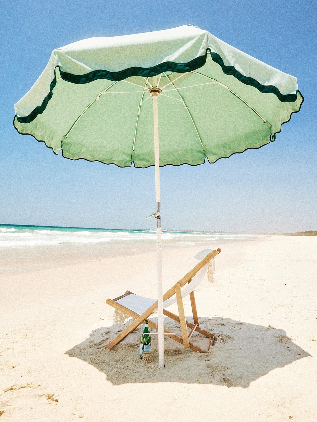 Beach club umbrella and white chair on the beach