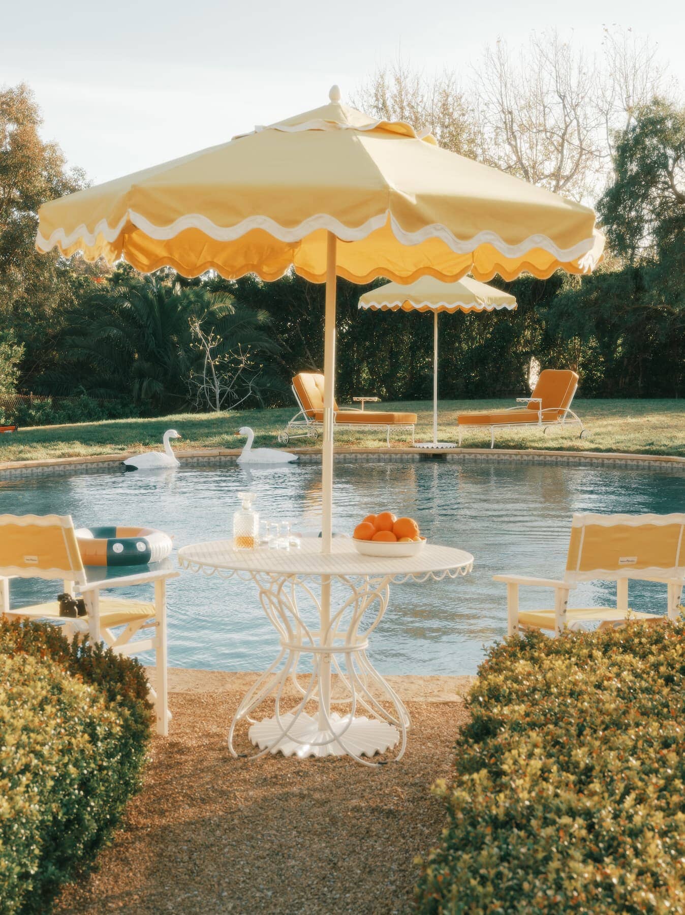 Riviera mimosa chairs, umbrellas and tables next to a pool