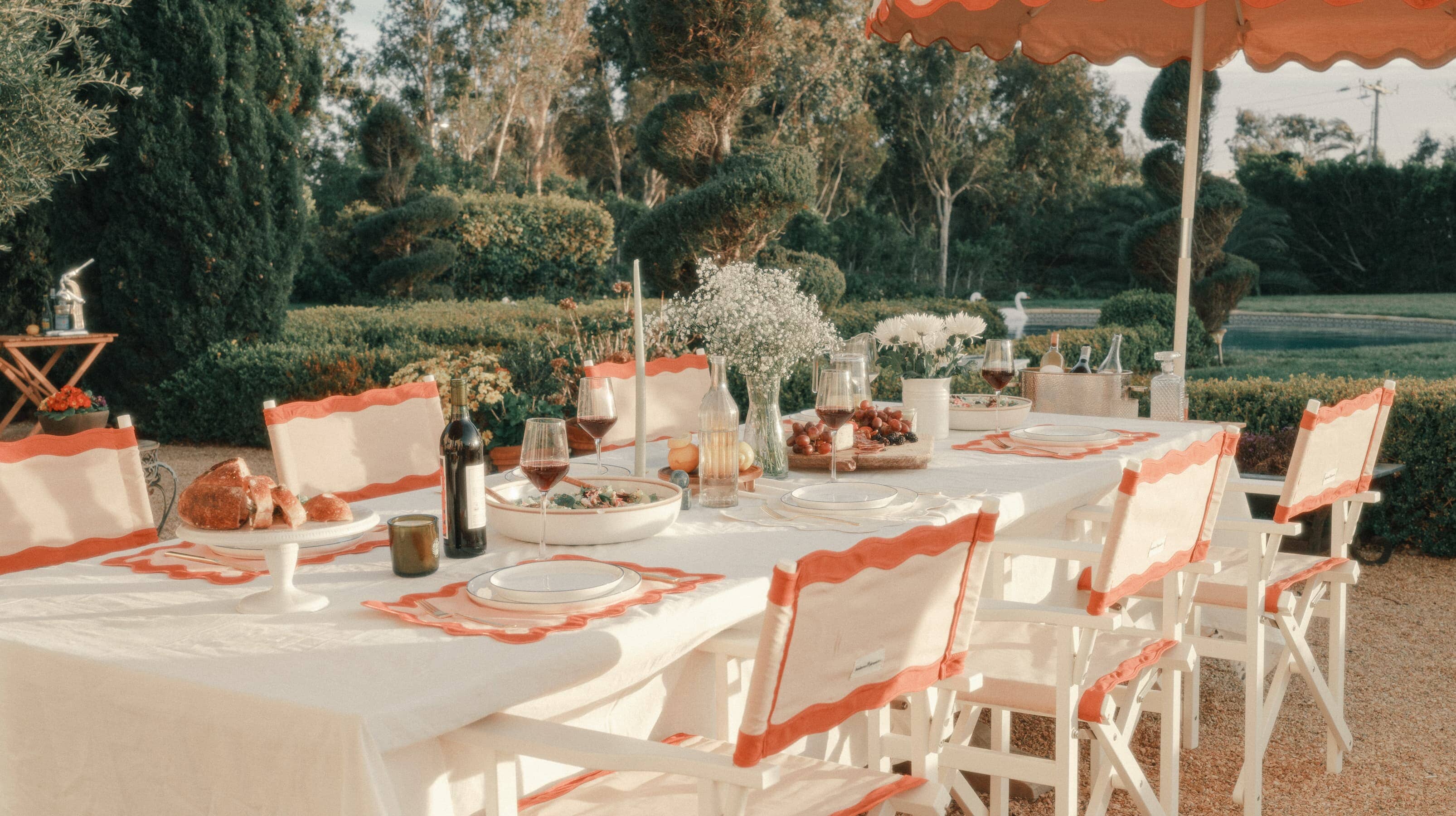 Riviera pink directors chairs and umbrellas at an outdoor dining table