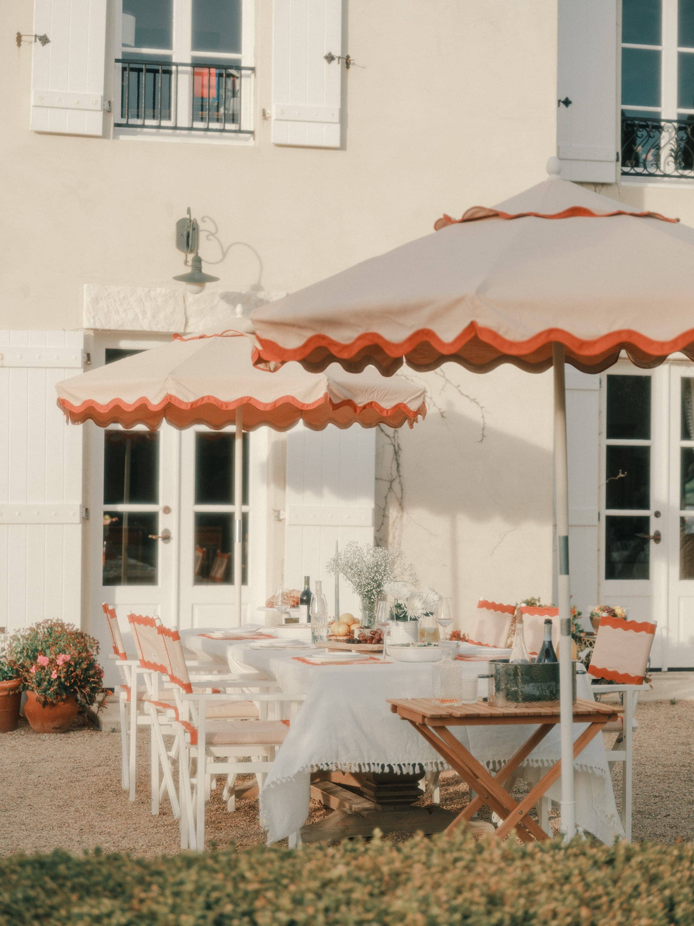 Outdoor patio setting with riviera pink market umbrellas, chairs and white table