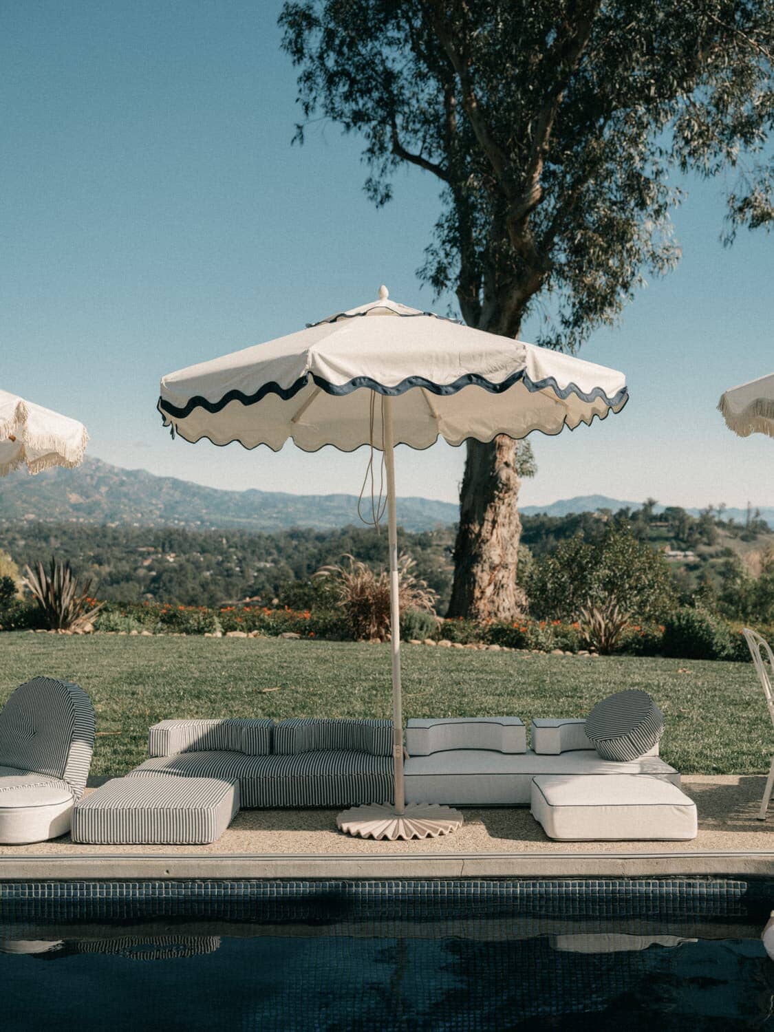 Outdoor pool setting with riviera white market umbrella and outdoor modular cushions.