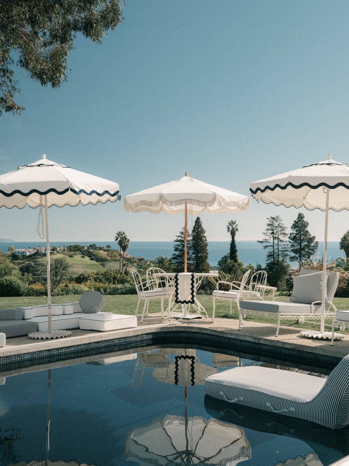 Outdoor pool setting with riviera white market umbrella, table and chairs. 