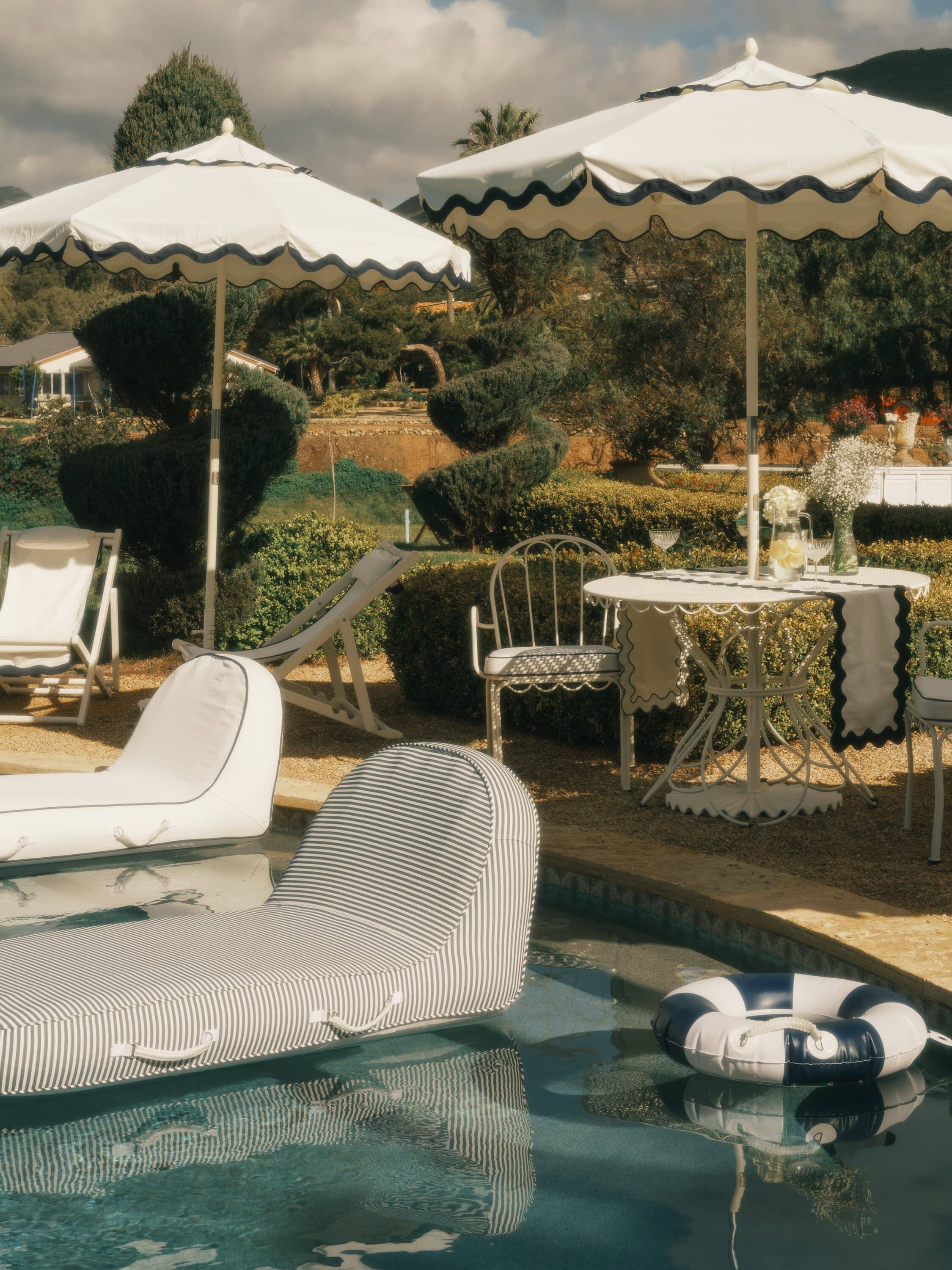 Pool with pool loungers, floats, umbrellas and chairs