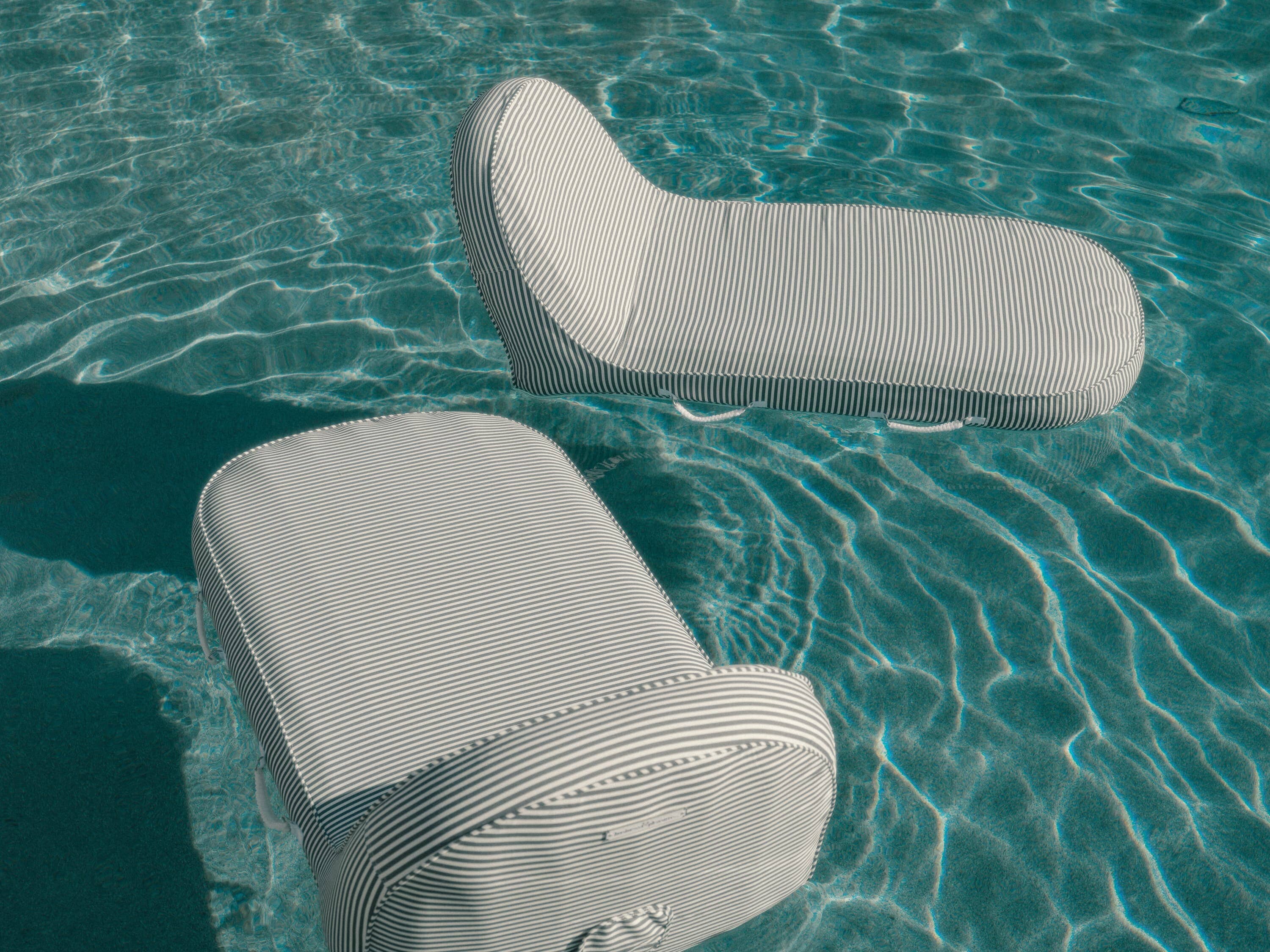 Navy pool loungers floating in a pool